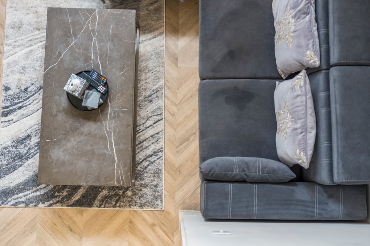 Overhead view of the living space at Athenaeum House with the marble table, decorative box, wooden flooring and a dark grey sectional sofa with cushions