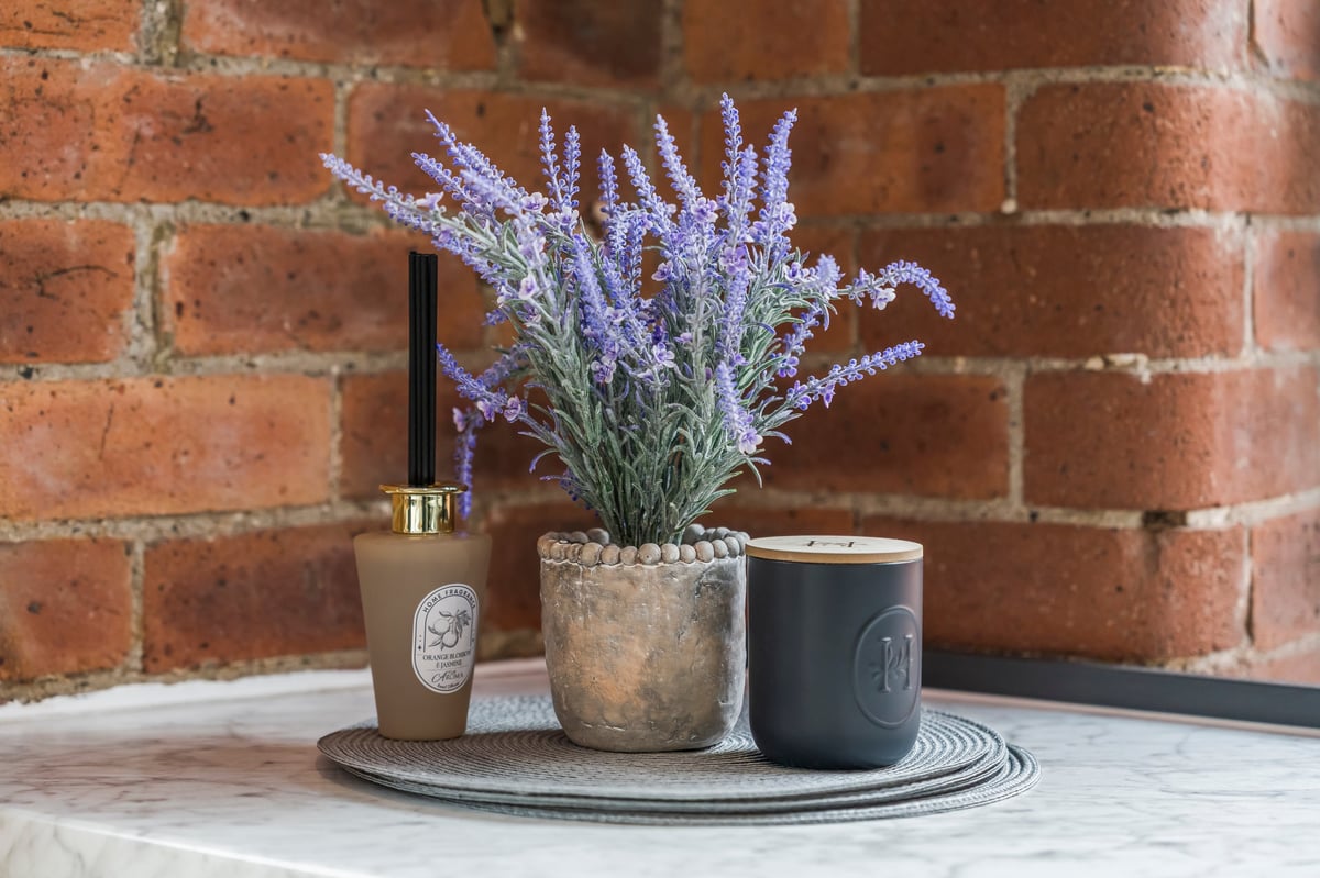 Potted lavender styled with candles and jars against a brick wall at The Calls