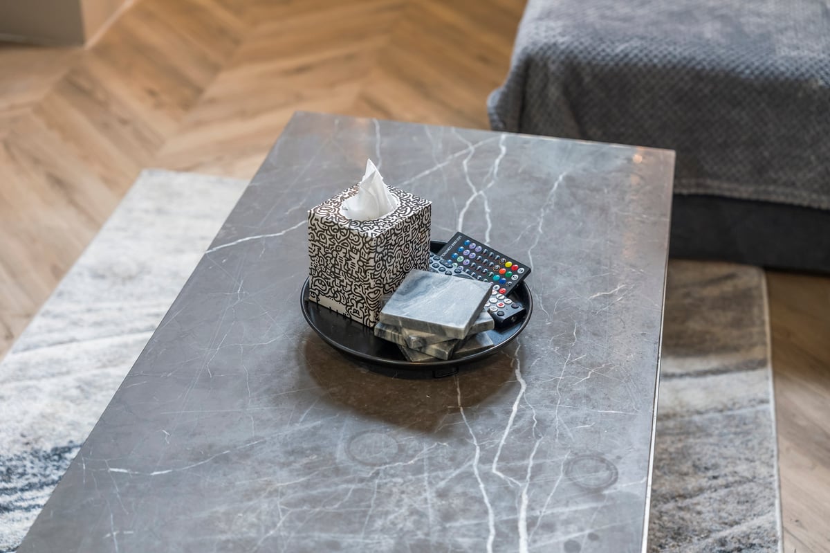 Grey marble coffee table at Athenaeum House with a decorative tray holding a tissue box and a remote control
