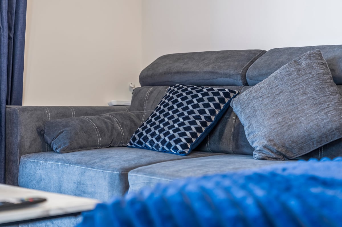 Grey upholstered sofa with decorative cushions including a blue patterned one in the living room at Wedgewood