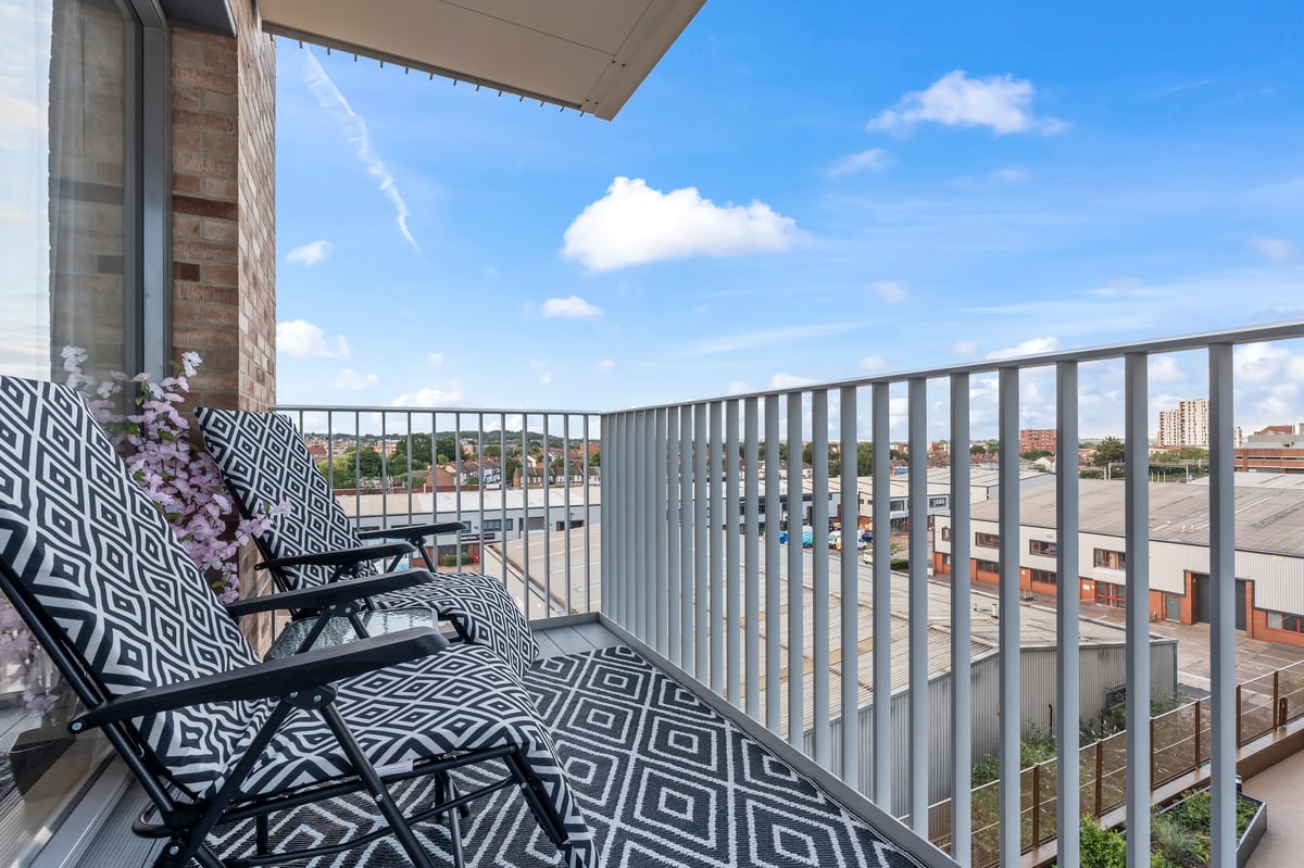 Balcony at Wedgewood with two black and white patterned outdoor chairs and a cityscape view under a clear blue sky