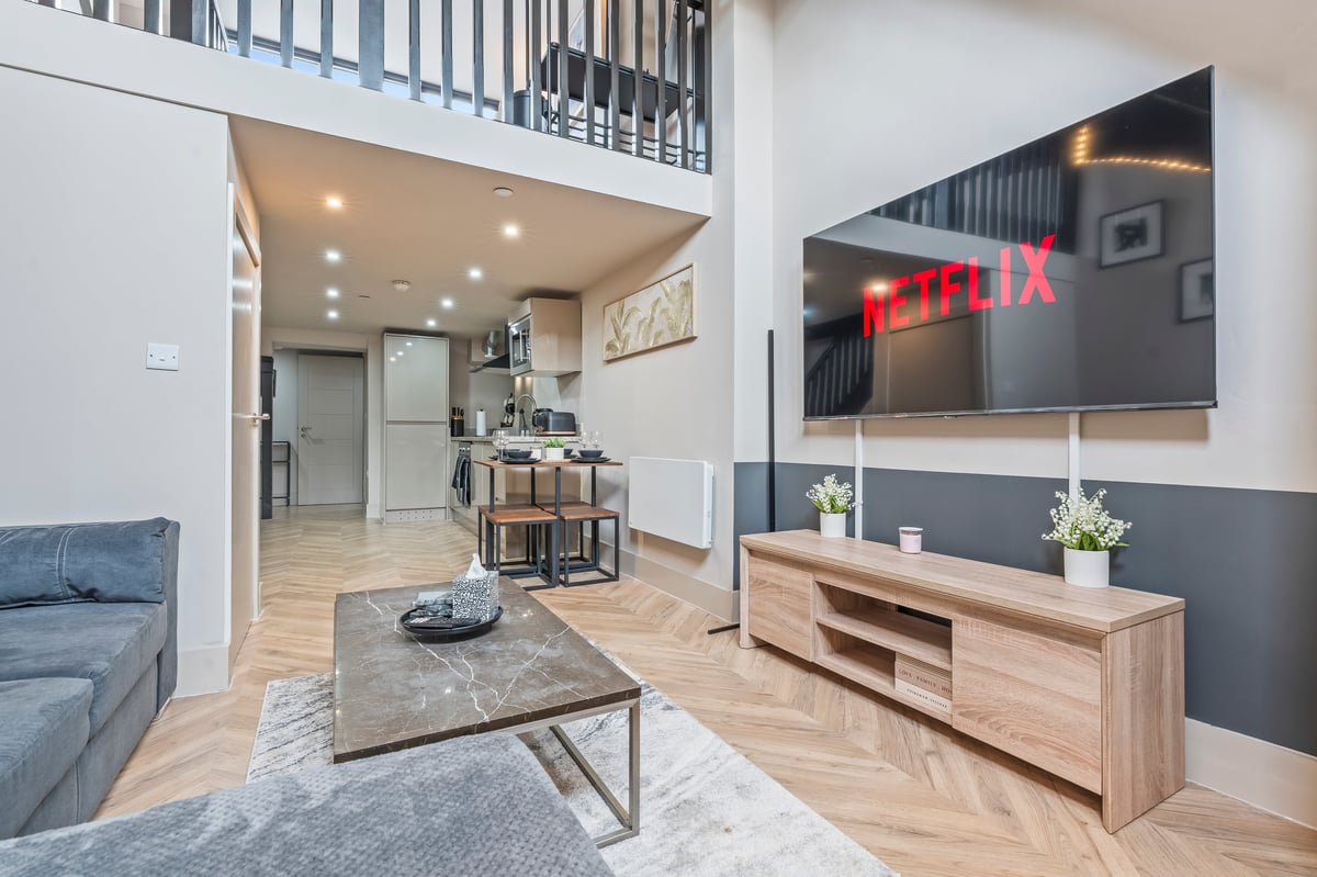 Open-plan living space at one of the AK Getaways apartments, with kitchen, dining area and sofa