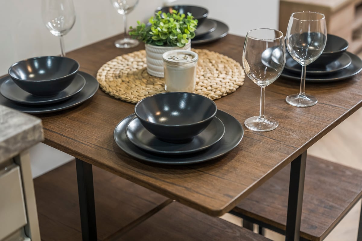 Dining table at Athenaeum House laid with black bowls and plates, wine glasses and a potted plant