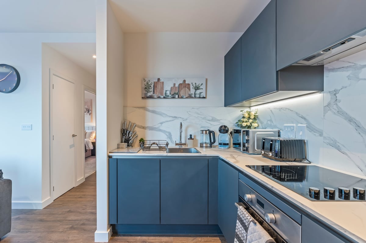 Kitchen at Wedgewood with blue cabinetry, a marble splashback, wooden countertops and the hallway entrance adjoining it
