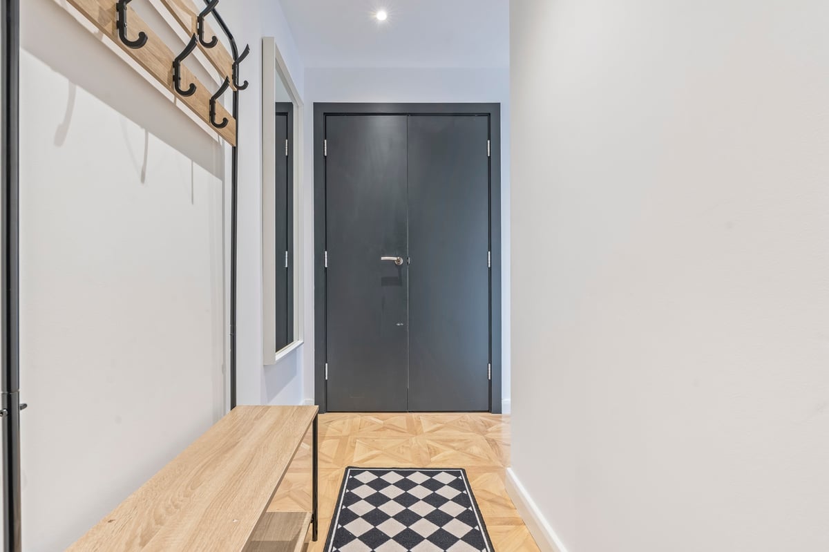 Entrance hall at The Calls with light wood flooring, a black and white tiled entryway and a dark grey front door