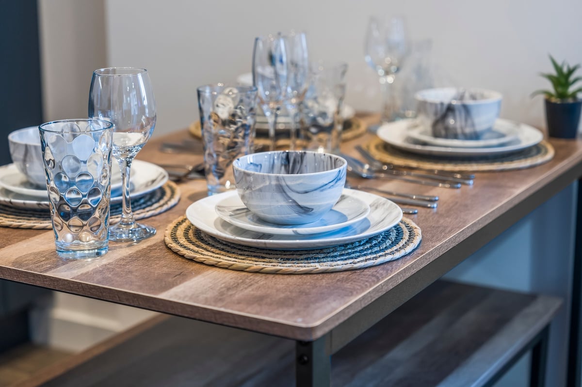 Formal table setting at Wedgewood with blue and white place settings, crystal glasses and woven placemats on a wooden table