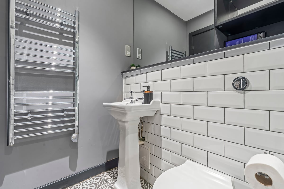 Bathroom detail at The Calls with a heated towel rail, pedestal sink and white subway tiling
