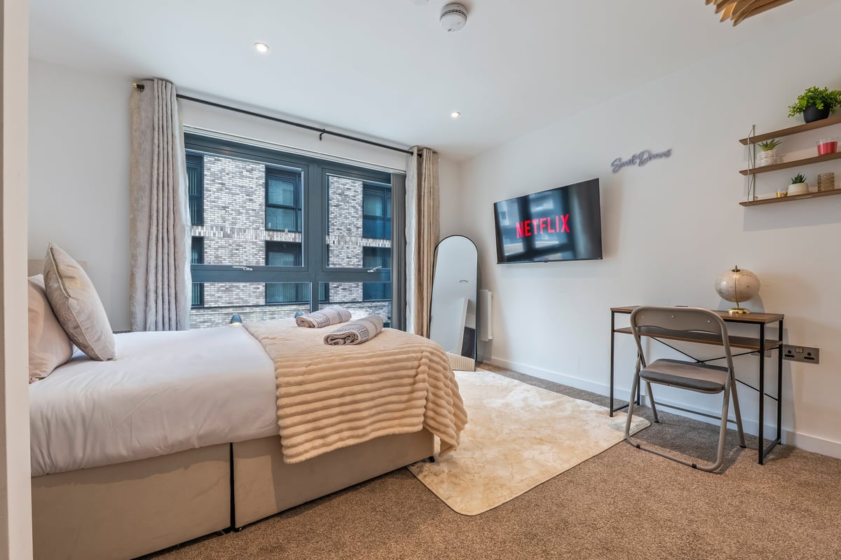 Bedroom at the Aspire apartment with a single bed, large windows, a work desk and contemporary furnishings