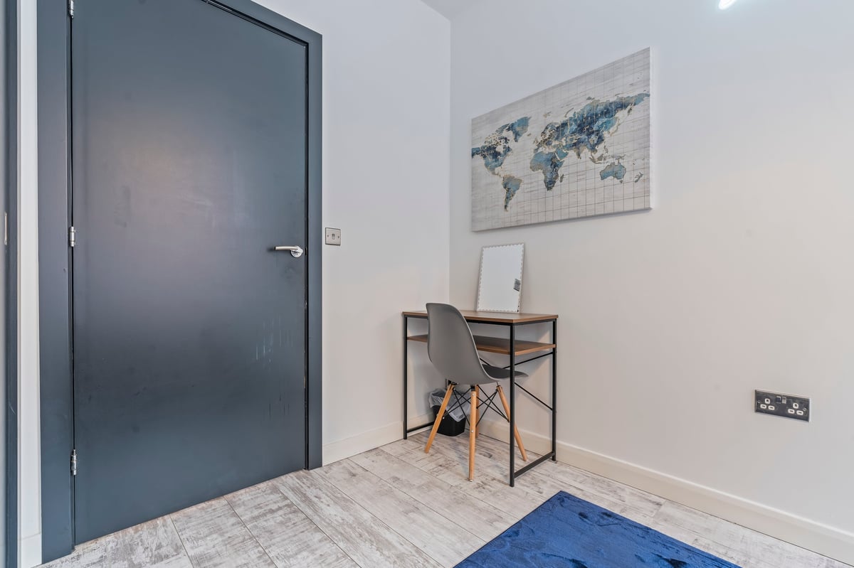 Entryway at The Calls with a dark blue front door, a small desk, map artwork and light wood flooring